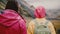 Back view of two young women with backpacks walking in mountains. Tourists hiking together early in the foggy morning.