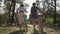 Back view of two young women in bright dressing talking while leading their bicycles on the narrow road on the street