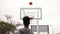 Back view of unrecognizable african player jumping up and throwing ball in a basketball hoop, the ball hits the ring and