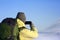 Back view of unrecognizable male in hat and backpack taking picture of amazing winter landscape