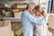 back view of upset senior couple embracing while standing between cardboard boxes