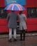 Back view of well-dressed young couple with British flag umbrella