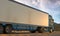 Back View Of White Semi Truck With Empty Space On Refrigerator Driving Through Desert. 3d rendering