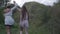 Back view wide shot of cheerful Caucasian slim mother and adult daughter holding hands and running along canyon on