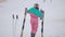 Back view wide shot of slim young woman in ski suit dancing in slow motion at ski resort. Happy joyful Caucasian tourist