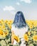 Back view of woman with blue hair standing in sunflowers field.
