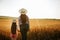 back view, woman and daughter child with hat on head examines farmland,