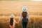 back view, woman and daughter child with hat on head examines farmland,