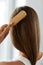 Back View Of Woman With Healthy Long Hair Brushing It With Brush