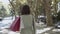 Back view of woman holding bags on shoulder and walking