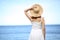 Back view of a woman holding pamela hat on the beach