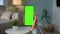 Back View of Woman at Modern Room Sitting on a Chair Using Phone With Green Mock-up Screen Chroma Key Without Track