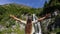 Back view of a woman outstretching arms celebrating in a waterfall