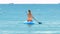 Back view woman paddles board among buoys