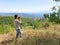 Back view of a woman photographer taking pictures of the valley with mountains