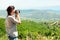 Back view of a woman photographer taking pictures of the valley with mountains from above