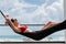 Back view of woman in red bikini resting in hammock with ocean view on rooftop of a luxury hotel.