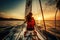 Back view of a woman riding a sailing boat at sunset in sea.