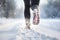 Back view of woman\\\'s legs jogging in snow