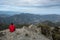 Back view of a woman standing on rocky top y enjoying mountain range panorama. Hiking traveling and climbing