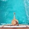 Back view of woman in straw hat relaxing in turquoise swimming p