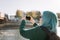 Back view of woman taking a photo of bridge