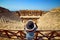 Back view of woman traveler in hat looking at amazing Amphitheater ruins in ancient Hierapolis, Pamukkale, Turkey. Grand panorama