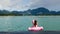 Back View of Woman on Vacation Sitting and Swimming on Pink Floating Flamingo