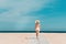 Back view of a woman walking towards the sea. Woman alone exploring mediterranean sea beach during summer sunny day