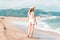 Back view of a woman walking towards the sea. Woman alone exploring mediterranean sea beach during summer sunny day