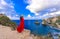 Back view woman wearing a red dress on the edge of a cliff looking at Diamond beach, Nusa Penida. Scenic view of Diamond Beach in