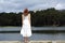 Back view of a woman in white dress contemplating in a lake