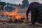 Back view of woman worker dries clay pots on fire