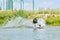 Back view of young active sportsman moving on surfboard and splashing water