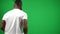 Back view young African American footballer walking on green screen from the left passing ball with hands. Confident