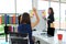 Back view of young Asian woman raising hands and asking a question during presentation in conference room