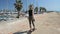 Back view of young attractive girl skateboarding along seafront