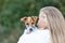 Back view of young beautiful woman holding  playing with Jack Russel terrier puppy outside. Small adorable doggy with funny fur