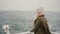 Back view of young blonde woman standing on the ship and looking wistfully on the sea, exploring the Iceland.