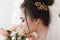 Back view of young brunette bride with barrette in hair. Flower bouquet on background. Close-up facial portrait