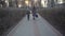 Back view of young brunette Caucasian woman and little schoolboy walking along the alley in city park in the evening