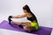 Back view of young, caucasian sportwoman sitting on violet fitness mat practicing yoga doing seated forward fold pose on white
