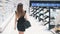 Back view of young Caucasian woman in black dress walking in cosmetics store.