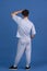 Back view of young curly man standing isolated over blue, navy studio background. Copyspace for ad, design. Concept of