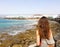 Back view of young female looking to Lanzarote beach landscape in windy day, Canary Islands, Spain