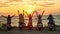 Back view of young friends, motorcycle riders raised their hands while standing with scooters on the beach and enjoying