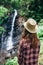 Back view of young girl from afar admires waterfall