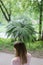 Back view of young girl with fern umbrella looking at park