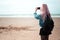 Back view of young girl with pink hair and black backpack admiring the sea with smartphone in hand.