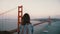 Back view young happy peaceful tourist woman with backpack and wind in her hair watching iconic Golden Gate Bridge view.